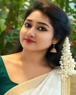 Priya in a green blouse and cream saree with the garden behind her