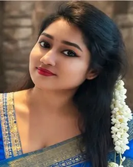 Priya glancing over her shoulder, jasmine in her dark hair and a blue saree border