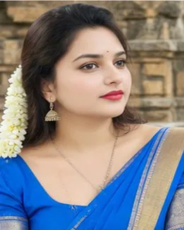 Divya in a blue saree in front of a carved stone wall