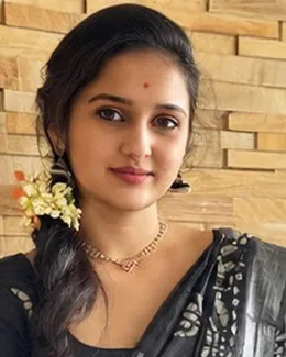 Pooja in a black printed saree beside a sandstone brick wall