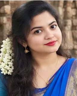 Ananya in a blue saree with gold jhumkas against an old stone wall